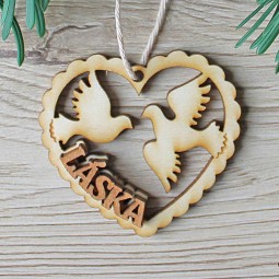 Vyrezávaná drevená vianočná ozdoba s textom Láska a holubicami v tvare srdca.