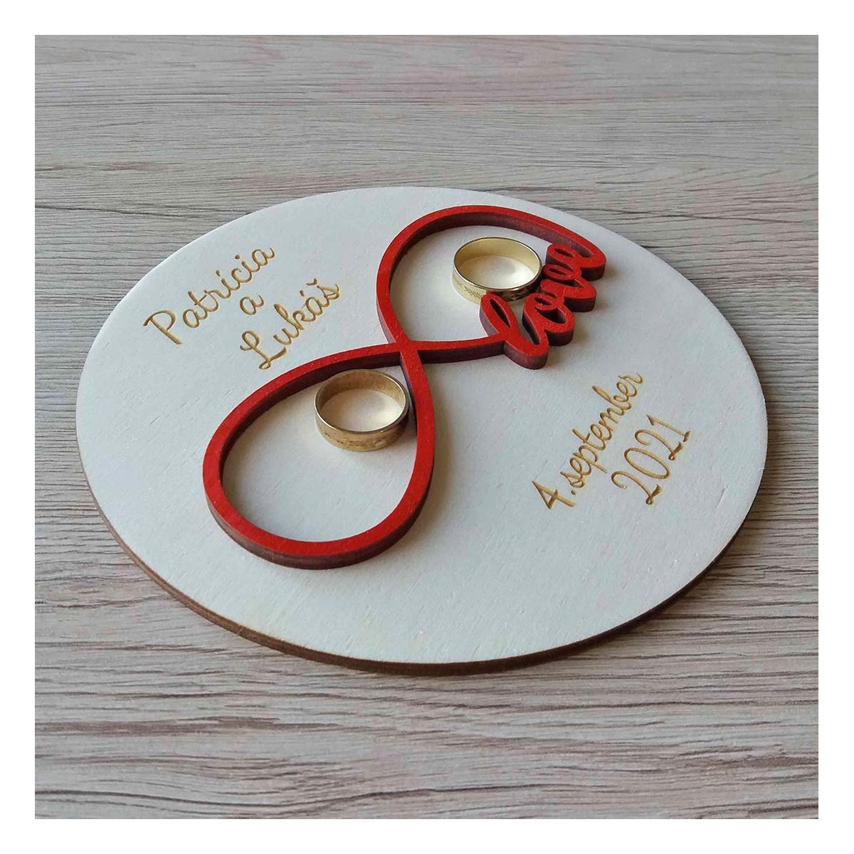 Drevený svadobný tanierik na obrúčky v tvare kruhu s výrezom nekonečnej lásky v červenej farbe a gravírovaným textom