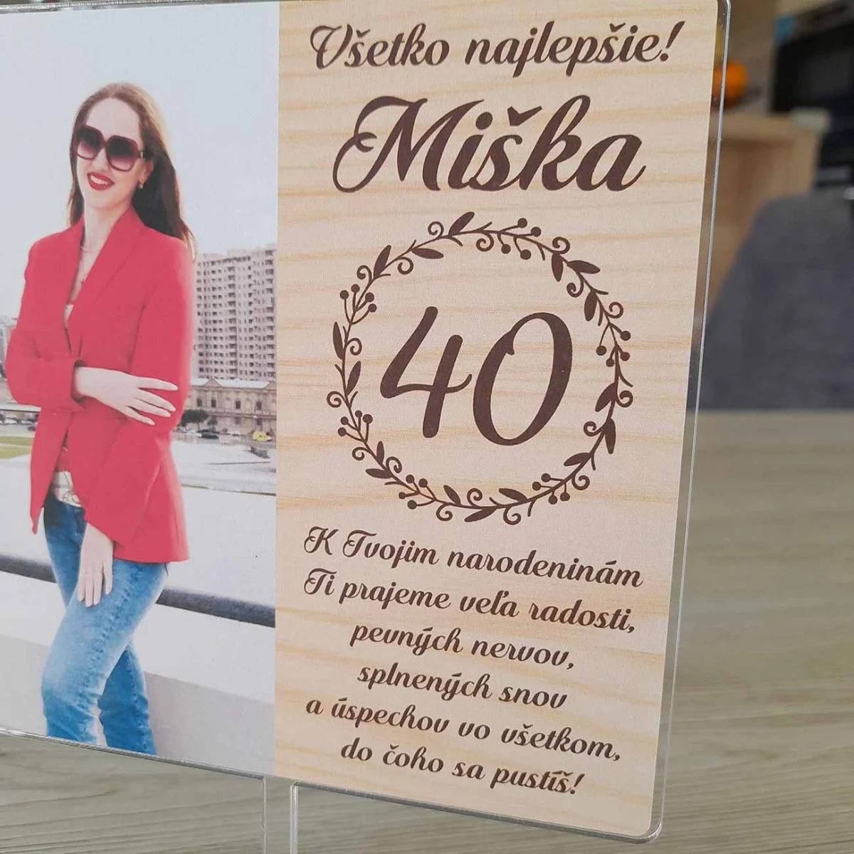 Detail obdĺžnikového zápichu na tortu s fotografiou a venovaním na pozadí s motívom dreva